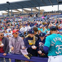 Seattle Mariners outfielder Teoscar Hernandez (35) signs autographs for fans before the start of a spring training game against the Chicago White Sox at Peoria Sports Complex