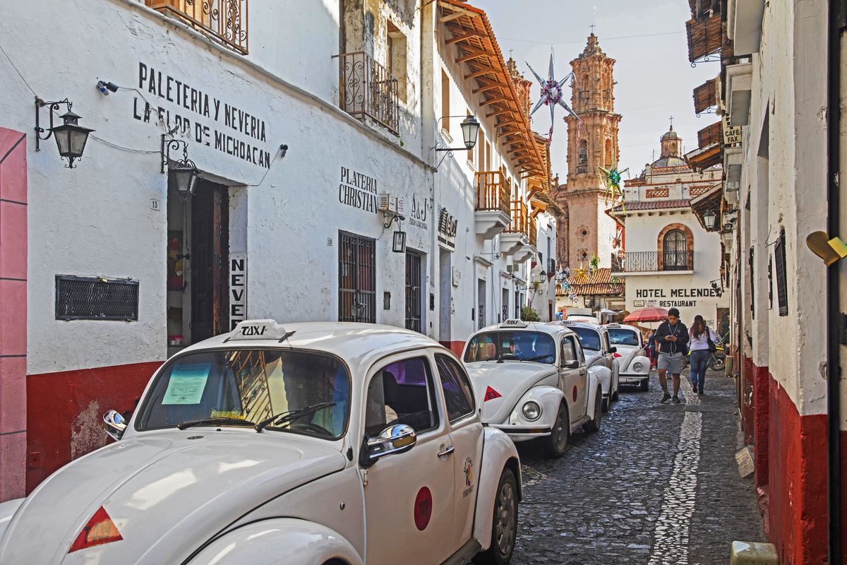 White Volkswagen Beetle taxis in narrow street in the colonial city centre of Taxco de Alarc—n, Guerrero, Mexico