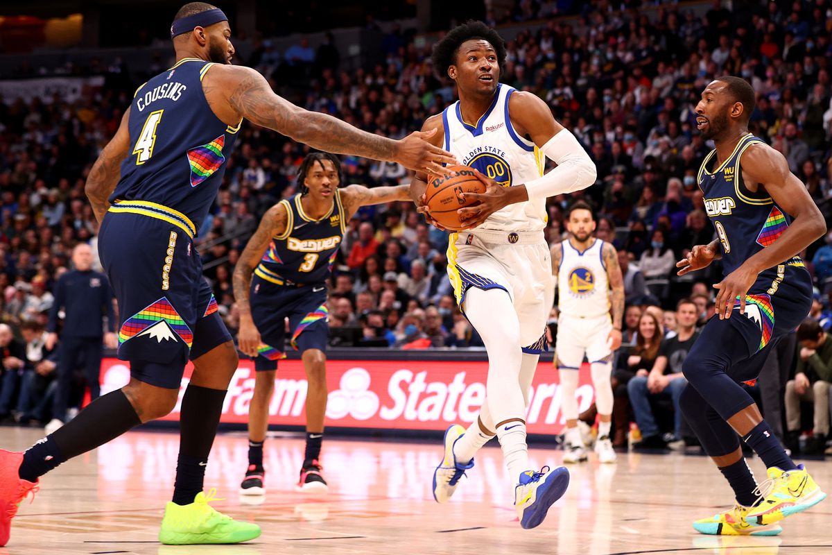 MARCH 07: Jonathan Kuminga #00 of the Golden State Warriors drives past DeMarcus Cousins #4 of the Denver Nuggets at Ball Arena on March 7, 2022 in Denver, Colorado.