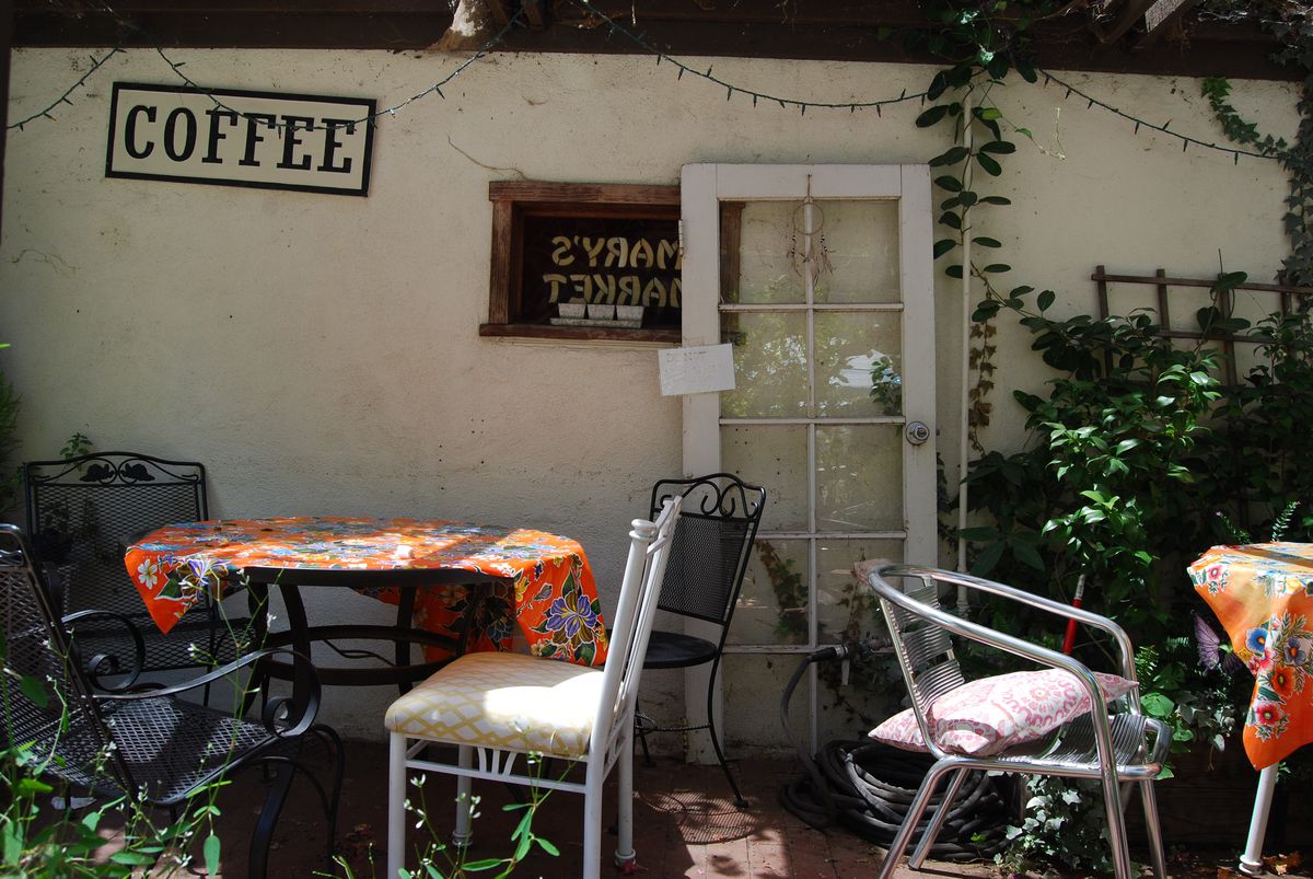 The exterior of Mary’s Market with outdoor tables and a sign that says coffee.
