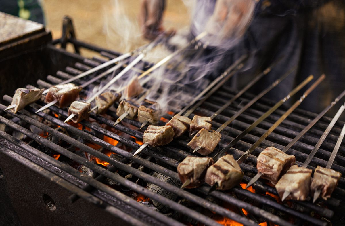 Skewers of fish on a grill expelling smoke.