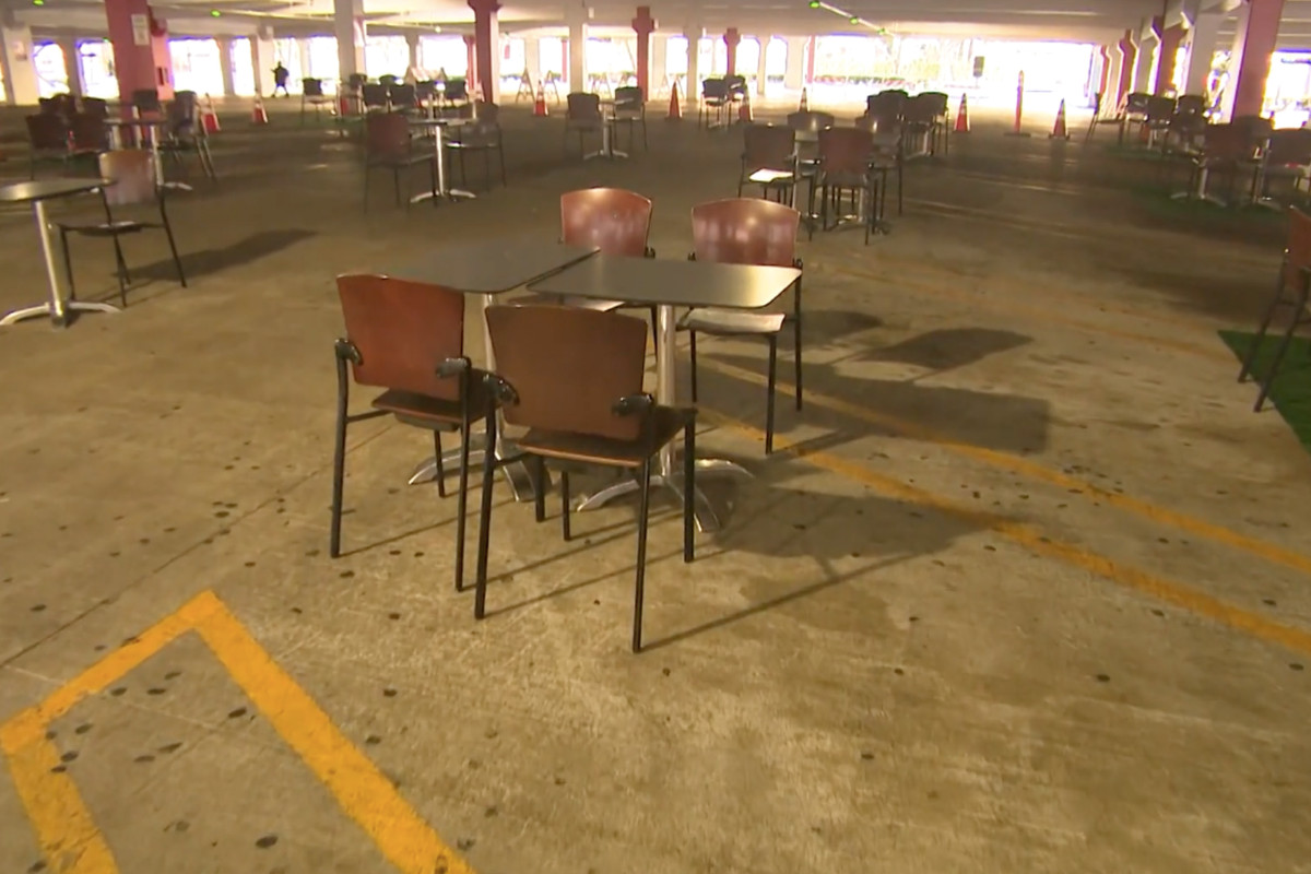 Tables set up inside of a parking structure to allow for outdoor dining during the coronavirus pandemic.