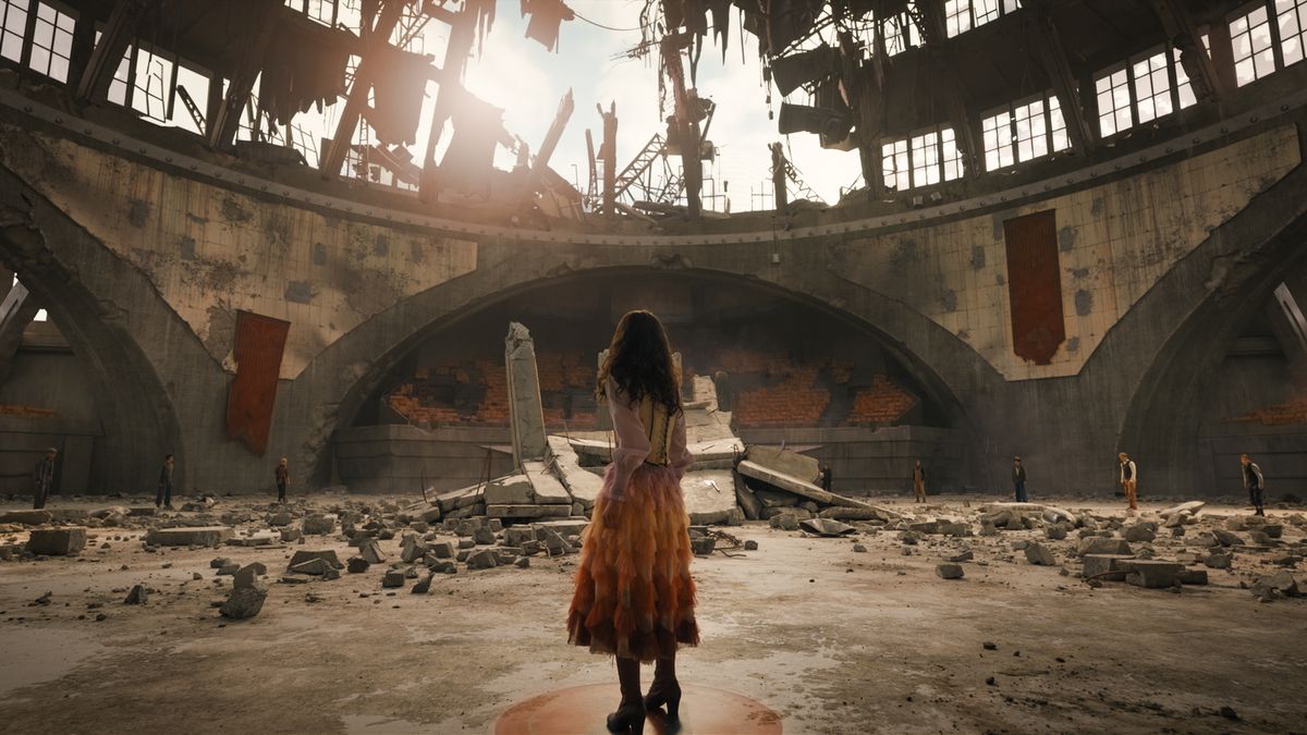 Lucy Gray standing in a ruined arena in The Hunger Games: The Ballad of Songbirds &amp; Snakes