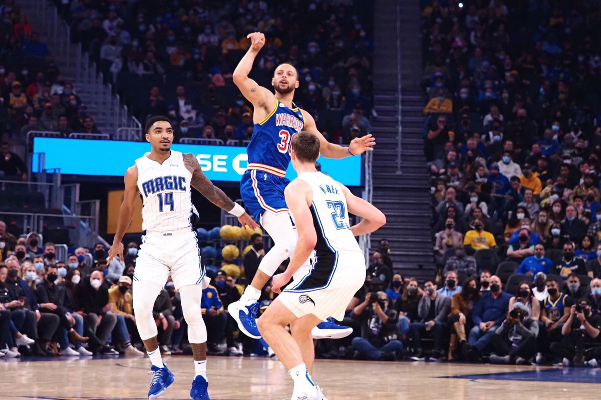 Golden State Warriors guard Stephen Curry (30) scores a long basket against Orlando Magic guard Gary Harris (14) and forward Franz Wagner (22) at the end of the first quarter at Chase Center.