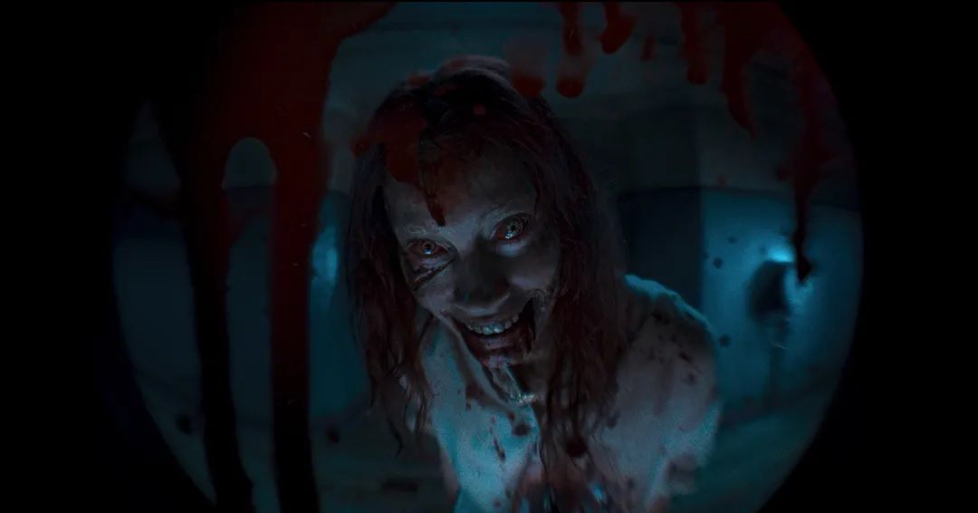 A deadite smiles wickedly in Evil Dead Rise, with blood all over the place.