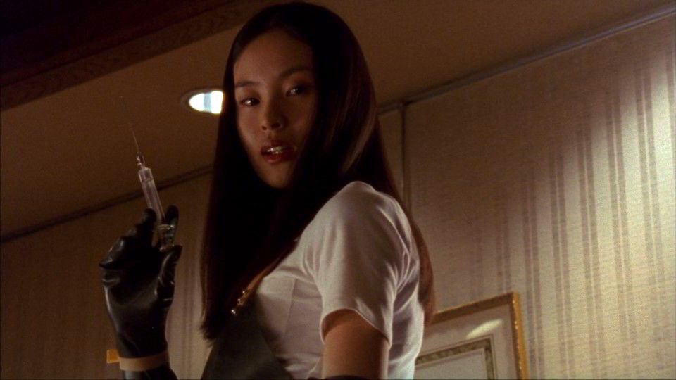 A woman in a white shirt with black gloves prepares a deadly syringe in Takashi Miike's audition