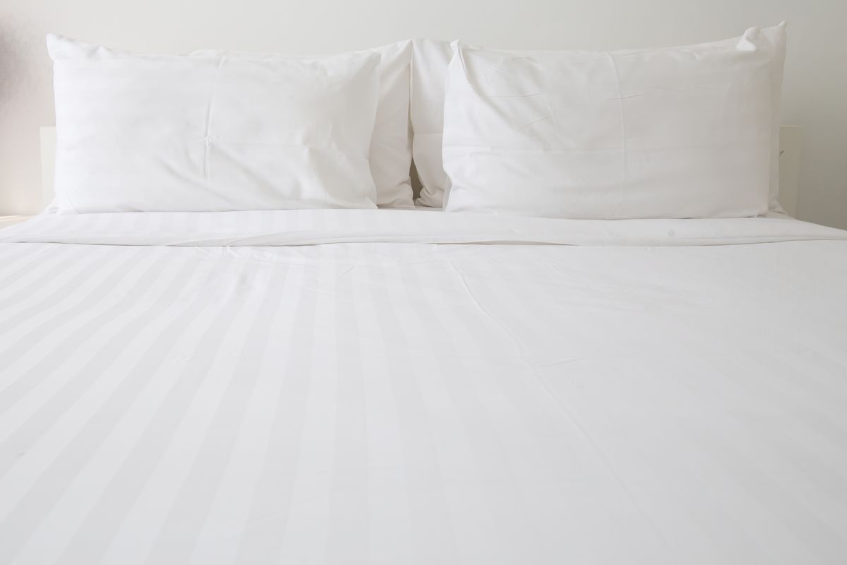 Clean white bed sheets on bed