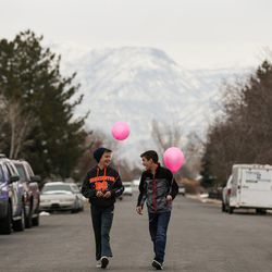 Jens Peterson, 13, and Warren Moses, 13, walk with pink balloons outside the Stilsons' home in Orem on Saturday, Dec. 3, 2016.