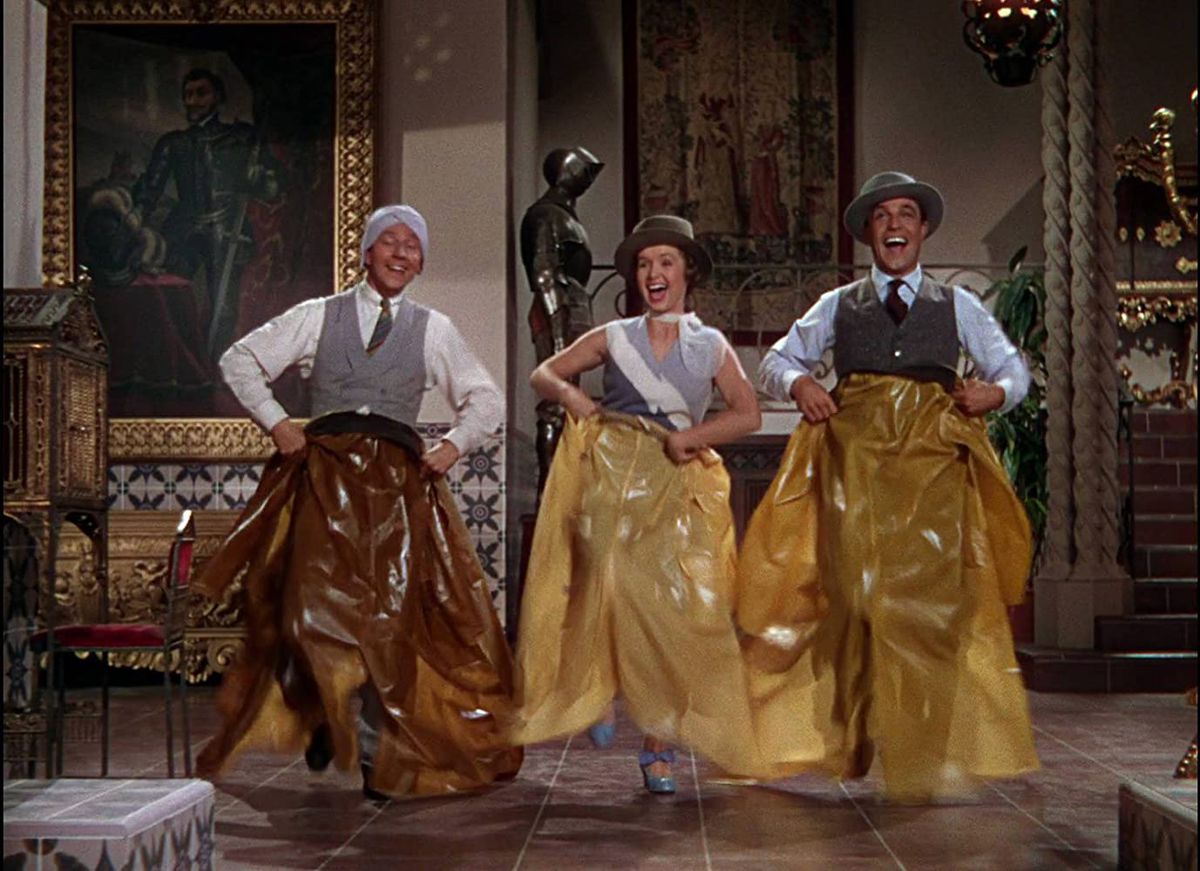 Gene Kelly, Debbie Reynolds, and Donald O’Connor dance with raincoats