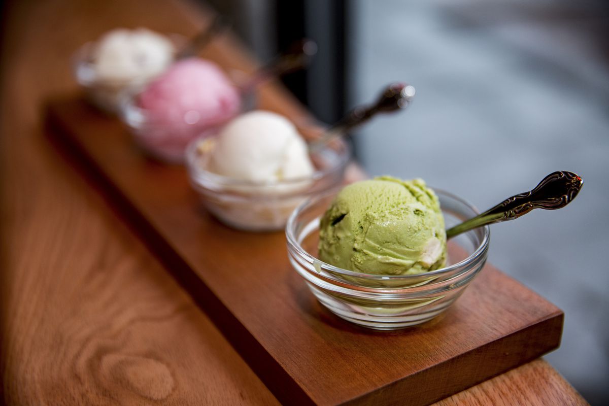 Four colorful bowls of ice cream from Salt and Straw on a wooden board.