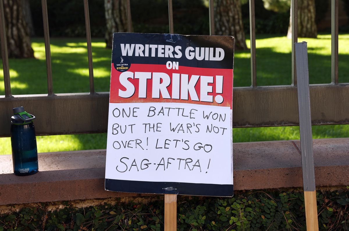 A picket sign that reads, “Writers Guild on strike!” Handwritten underneath, it says, “One battle won but the war’s not over! Let’s go SAG-AFTRA!”