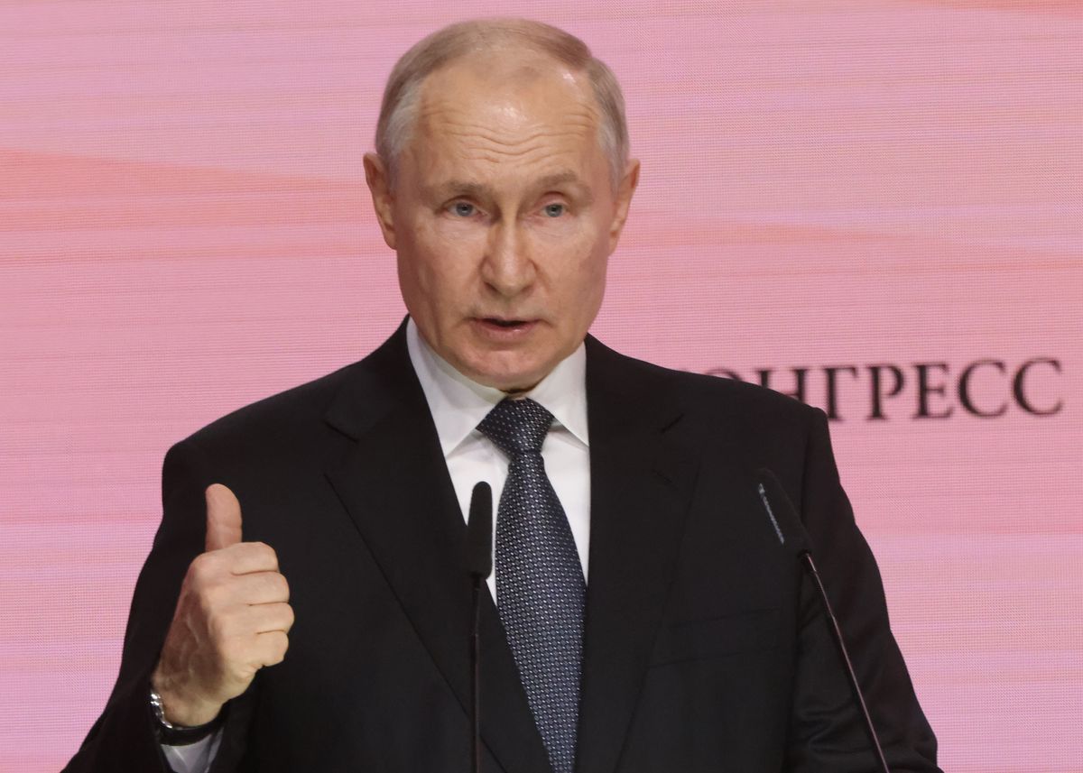 Putin in a suit at a lectern. 