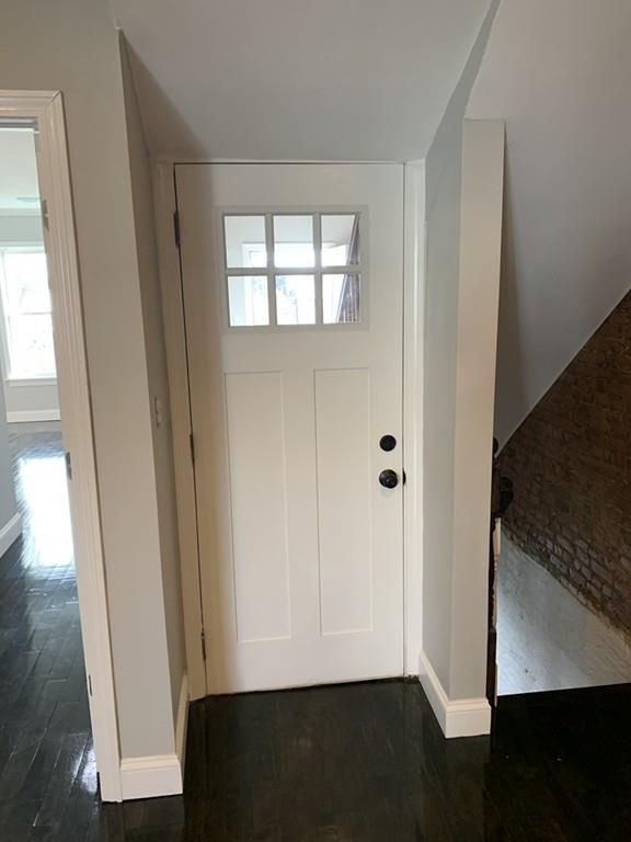 The front door of a newly renovated condo with a stairwell next to it leading down. 