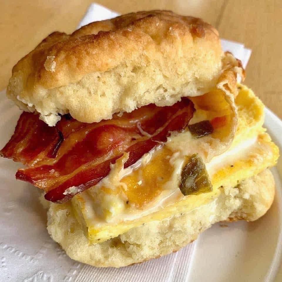 An egg and bacon biscuit sandwich on a napkin.