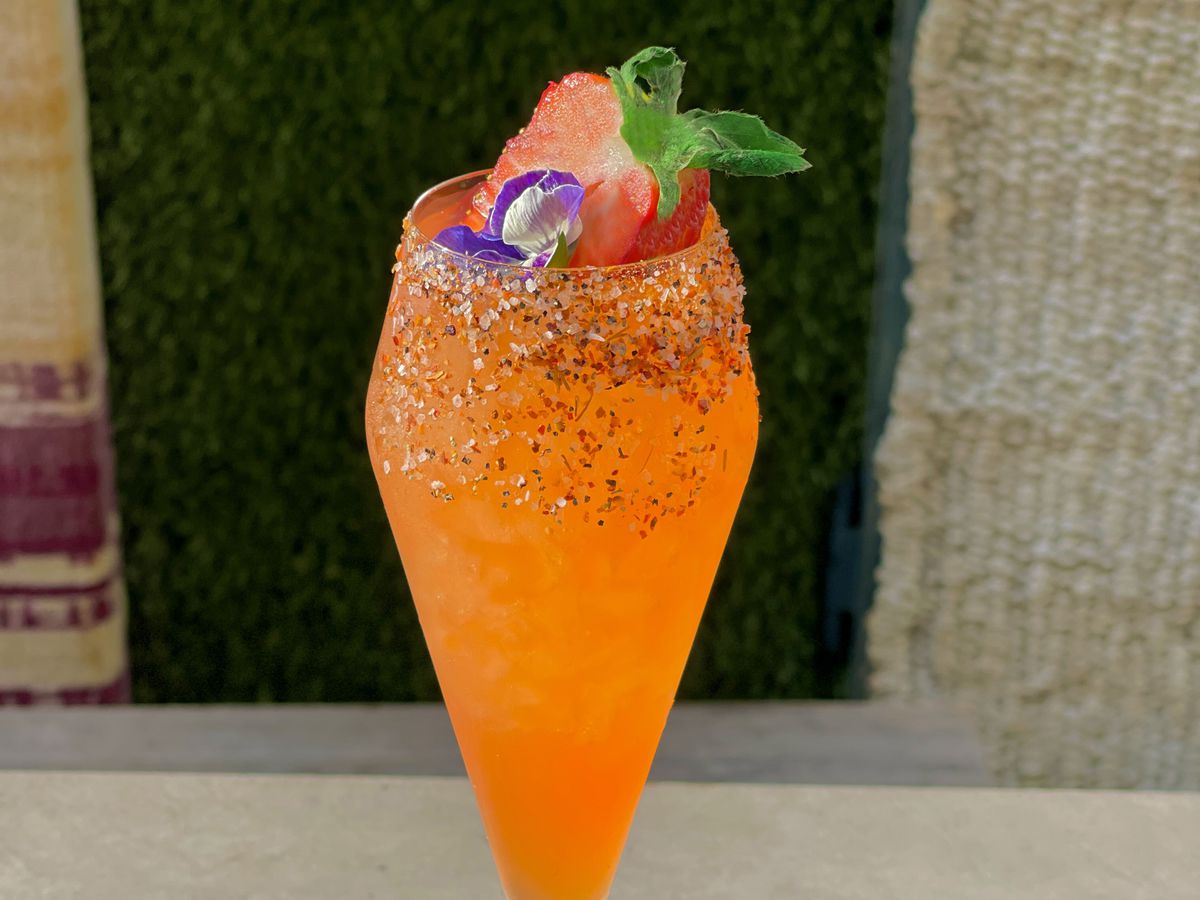 The La Rosa cocktail at Palmilla. It is orange, in a champagne glass, with salt on the rim and topped with a flower and a strawberry.