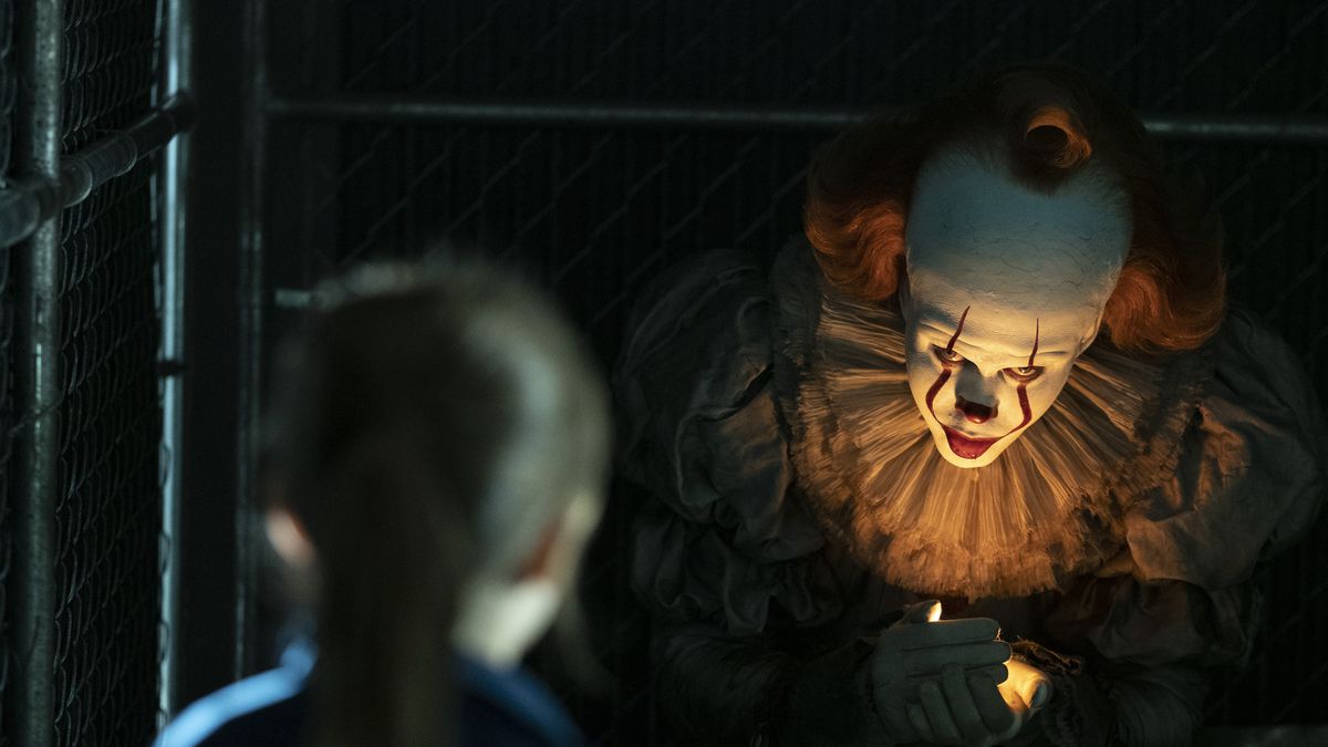 Pennywise, a frightening-looking clown, looms out of the darkness.