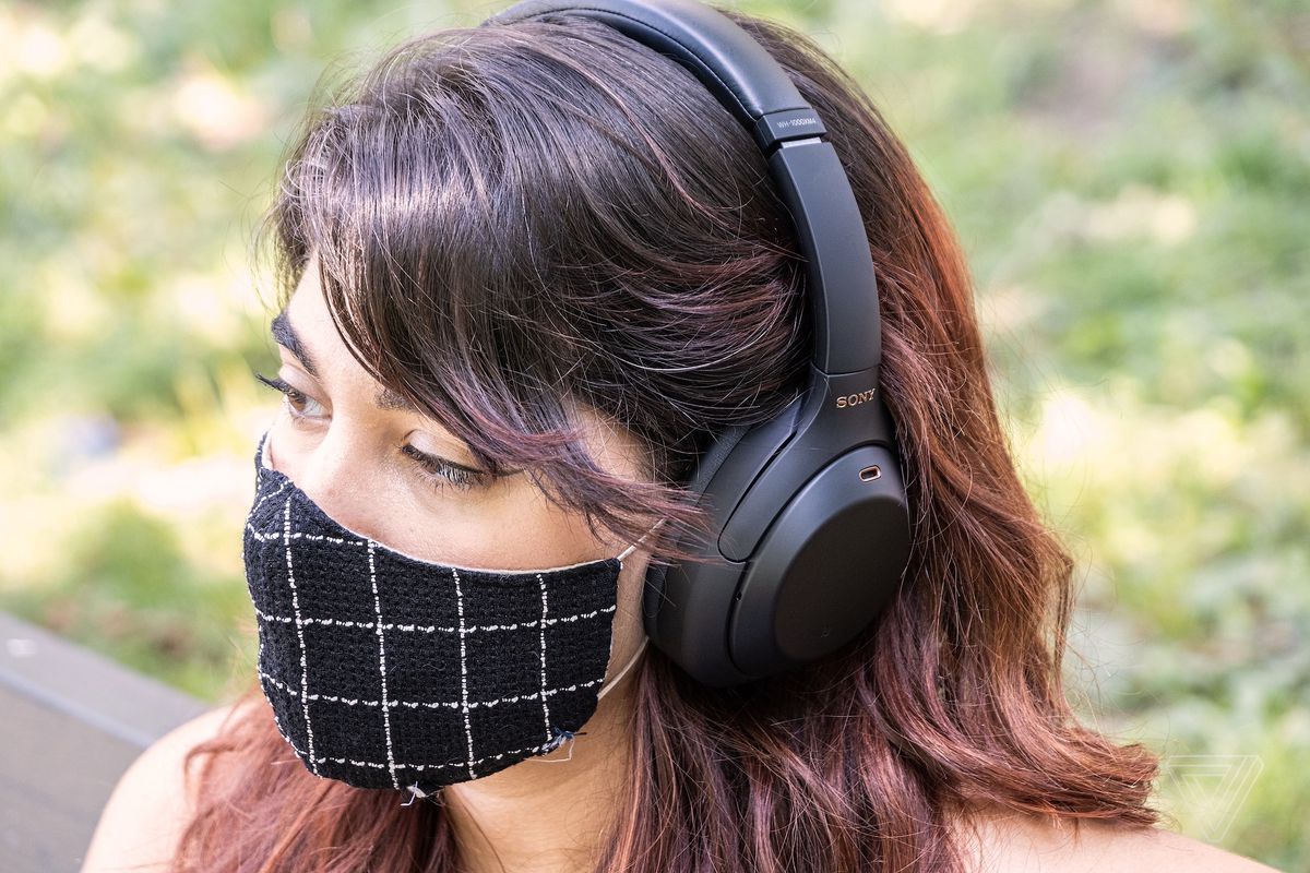 A woman wearing headphones and a mask