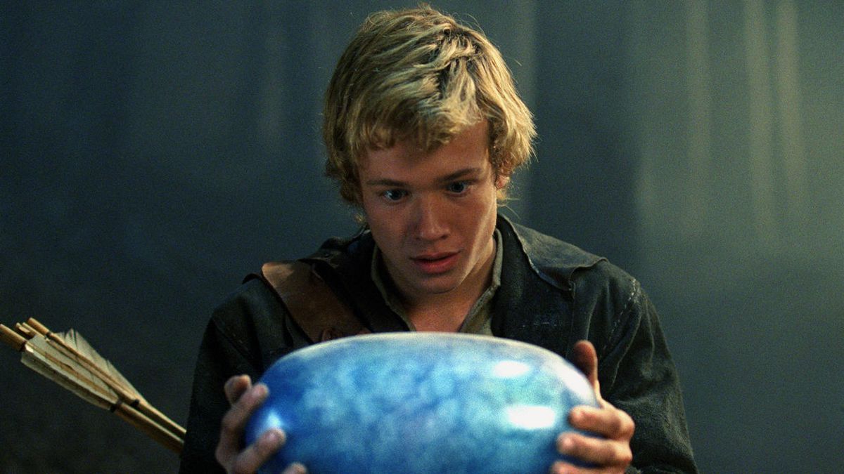 a blond young man holding a blue dragon egg