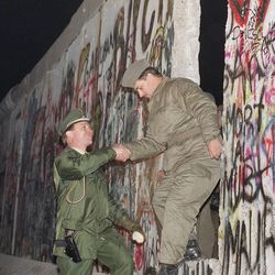 A West German policeman, left, gives a helping hand to an East German border guard who climbs through a gap of the Berlin Wall when East Germany opened another passage at Potsdamer Platz in Berlin, Nov. 12, 1989.