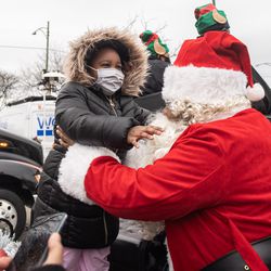 Aubrey Broughton, sister of 7-year-old Serenity, who was fatally shot in August in an alley on the Northwest Side, is carried by Early Walker dressed as Santa Claus on the parking lot of the 5th District Police Station in the Pullman neighborhood, Friday morning, Dec. 24, 2021. Police officials and Walker, founder of the organization “I’m Telling Don’t Shoot,” distributed Christmas gifts to Broughton, who also had been shot in the chest and armpit when her sister was killed.