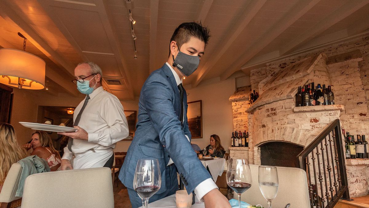 Servers at Selanne Steak Tavern place dishes at table in Laguna Beach on the restaurant’s first night of reopenings its dining room