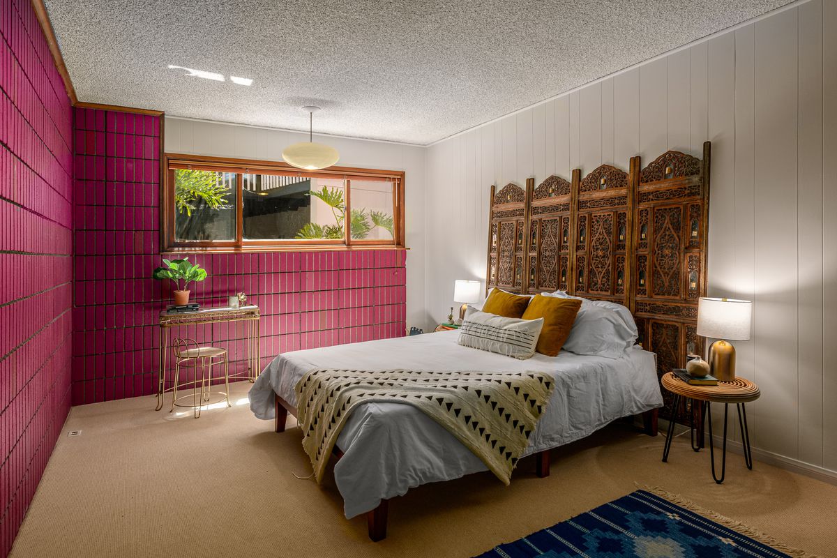 Bedroom with pink walls and beige floors. 