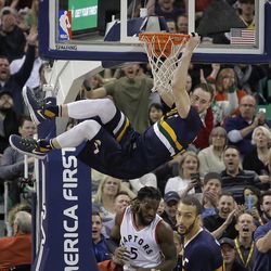 Utah Jazz forward Gordon Hayward, above hangs from the rim after dunking as Toronto Raptors forward DeMarre Carroll (5) defends and teammate Rudy Gobert, right, runs upcourt in the first half during an NBA basketball game Friday, Dec. 23, 2016, in Salt Lake City. 