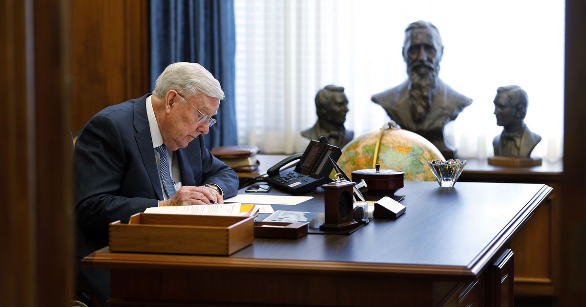 El presidente M. Russell Ballard trabaja en su oficina con esculturas de sus antepasados colocadas cerca.