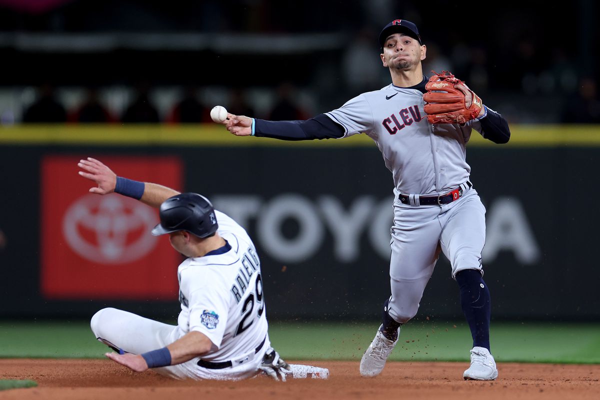 Andres Gimenez of the Cleveland Guardians turns a double play past Cal Raleigh of the Seattle Mariners during the fourth inning during Opening Day at T-Mobile Park on March 30, 2023 in Seattle, Washington.