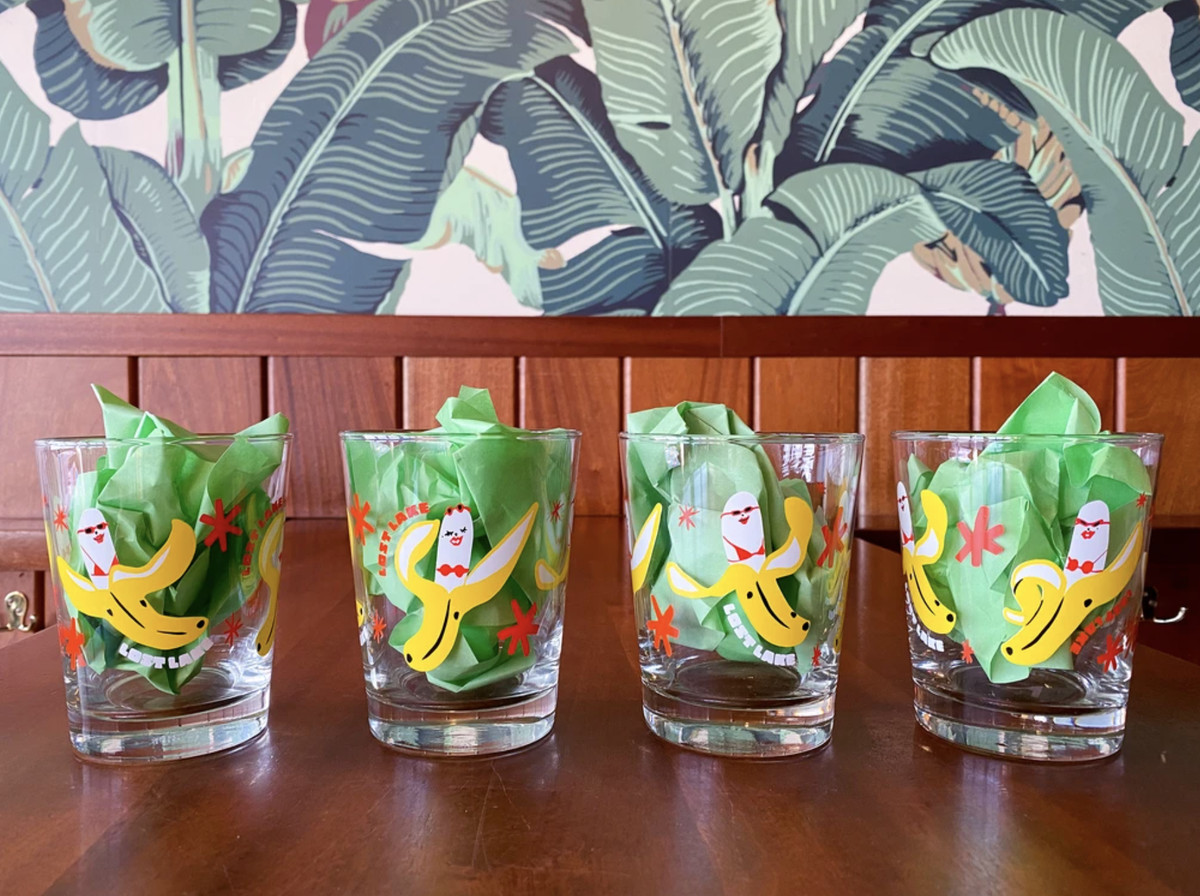 A row of four rocks glasses illustrated with bananas wearing bikinis