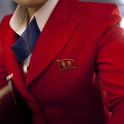 A North Korean Air Koryo attendant wears a pin showing portraits of the late North Korean leaders Kim Il Sung and Kim Jong Il, while she prepares the cabin before take off for Pyongyang from Beijing airport, in China, Thursday, April 11, 2013. 