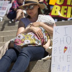 Magdalena Maczynska holds Zosia Farmer, 5, while sitting next to their sign at a rally protesting the separation of immigrant children from their parents at the Capitol in Salt Lake City on Saturday, June 30, 2018.