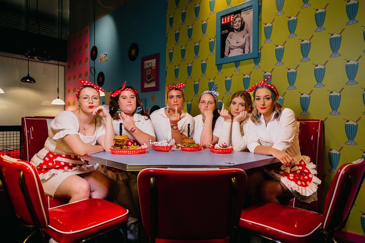 A group of women dressed as food servers sit at a table.