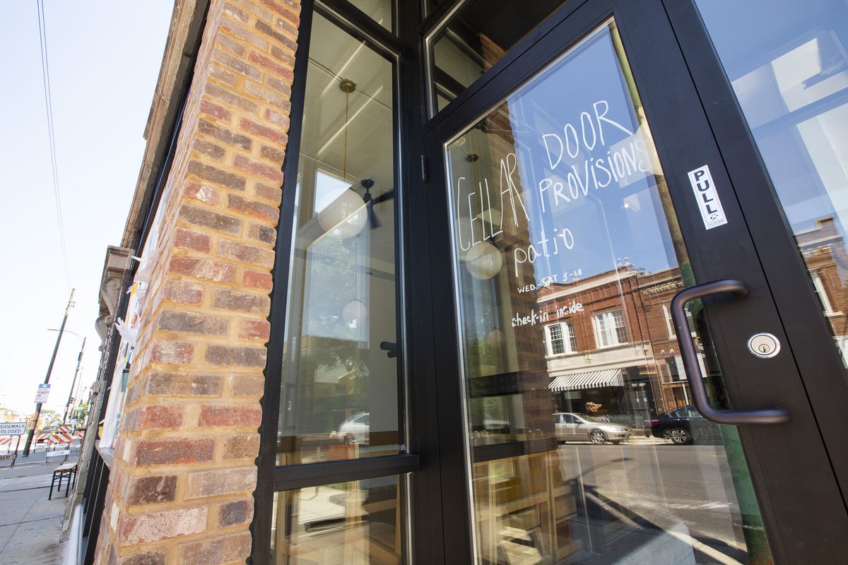 A glass door that leads into a brick building reads “Cellar Door Provisions.”
