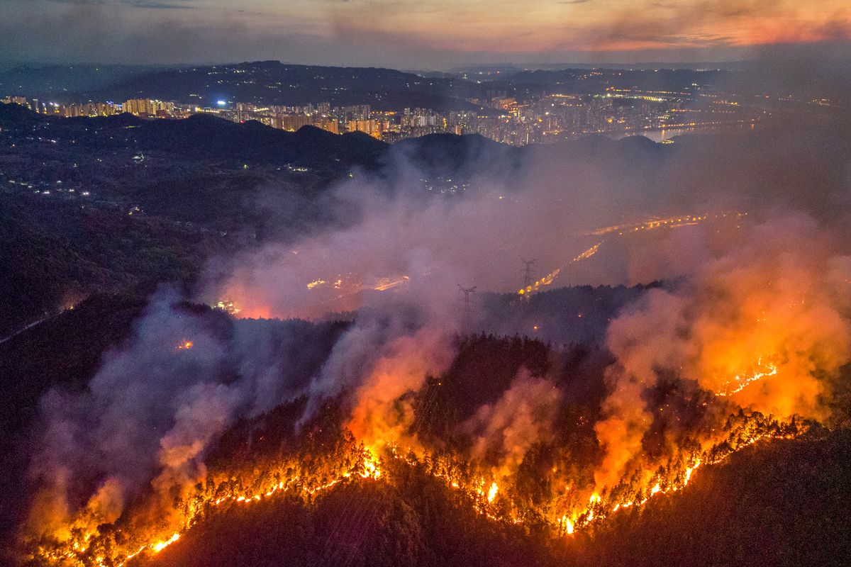 Smoke and flames rise from a mountain during a wildfire in Banan district on August 23, 2022 in Chongqing, China.&nbsp;