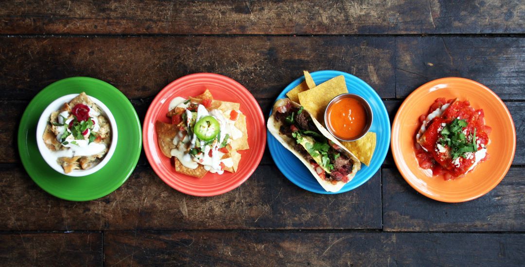 multi-colored plates topped with tacos and tortas. 