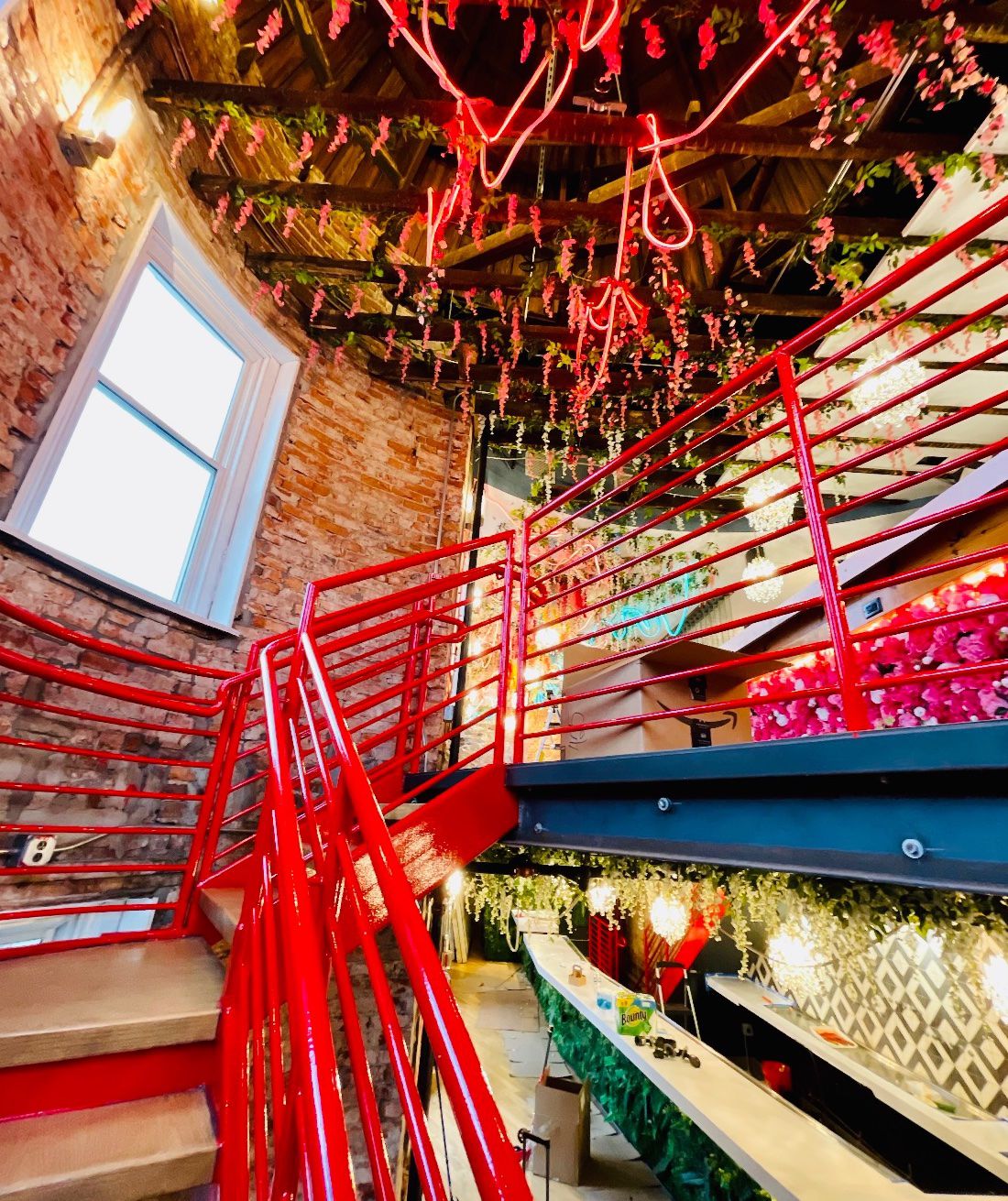 A red staircase framed by a brick wall and bar 
