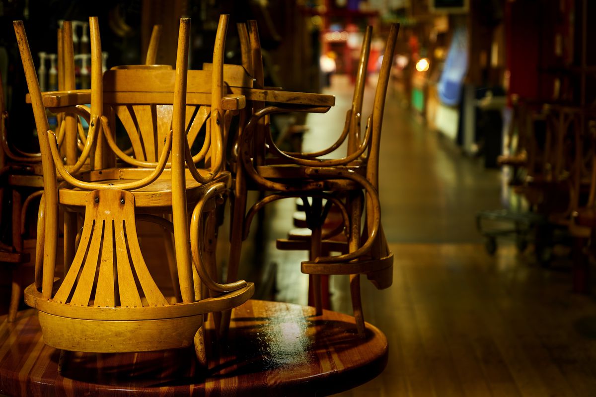 Light wood dining chairs stacked on tables in a dark restaurant.