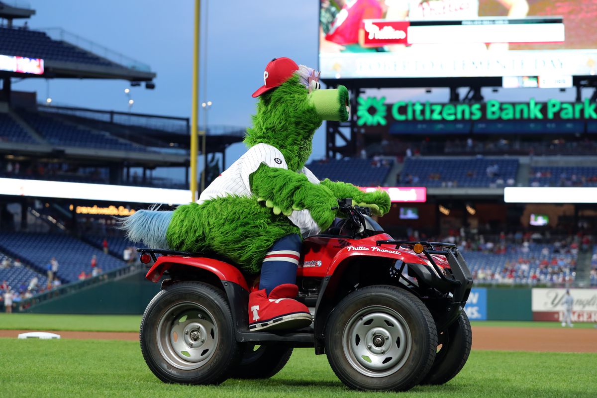 the Phillies mascot, a large, furry green bird called the phanatic, drives a four-wheeler on the field at citizens bank park in philly