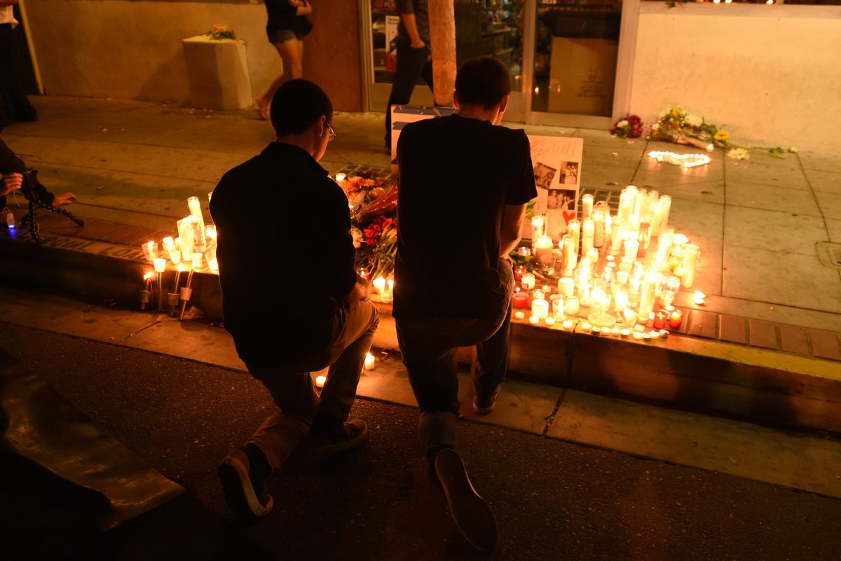 Two men kneel at a makeshift memorial after a killing rampage May 24, 2014 left seven people dead, in Isla Vista near Santa Barbara, California.