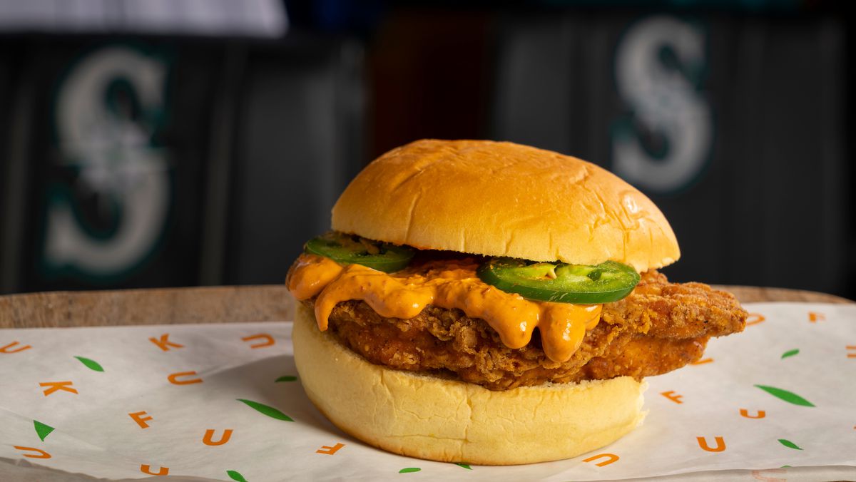 A fried chicken cutlet with some spicy, orange-colored mayo on top, and a few raw jalapeño slices, sandwiched in a bun.