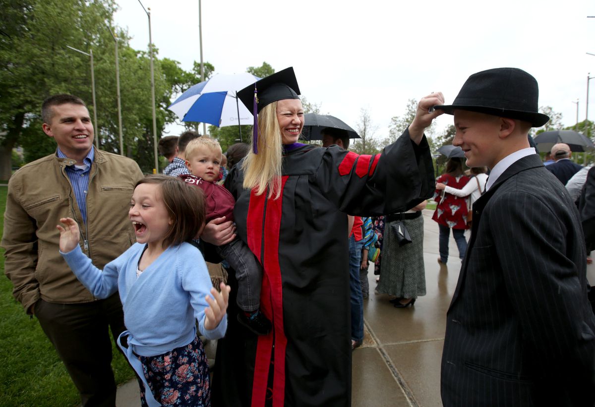 Kim Reeves holds son Gunnar and tugs on son Hunter's hat as daughter Brooke jumps and husband Jesse looks on after the S.J. Quinney College of Law commencement ceremony at the University of Utah in Salt Lake City on Friday, May 11, 2018. Reeves has two ot
