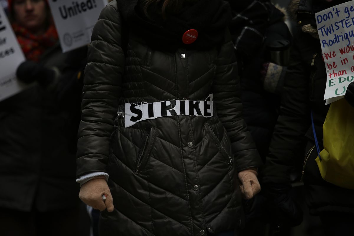 The word 'strike' is taped across a coat as educators from the Acero charter school network strike outside Chicago Public Schools headquarters on December 5, 2018