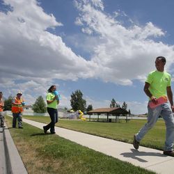 Lehi Parks employees walk around placing flyers on doors Wednesday, June 19, 2013, telling residents of a water restriction.