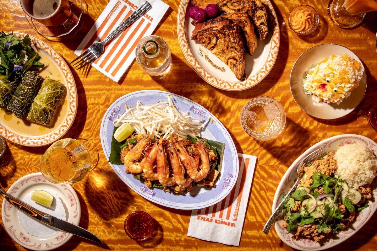 A spread of dishes shot from overhead, including verdant cabbage rolls, phat Thai noodles with pink head-on shrimp, fried chicken larb, and Thai tea pain perdu made from marbled babka.