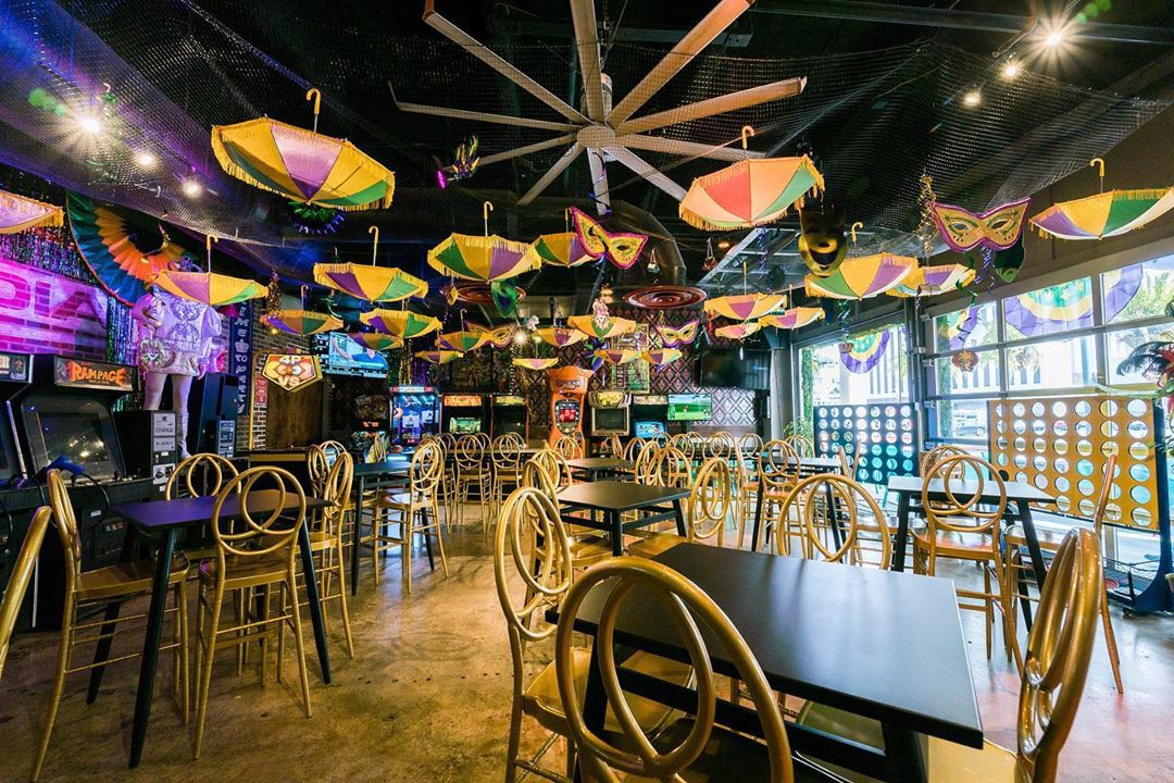 A bar with colorful umbrellas hanging from the ceiling