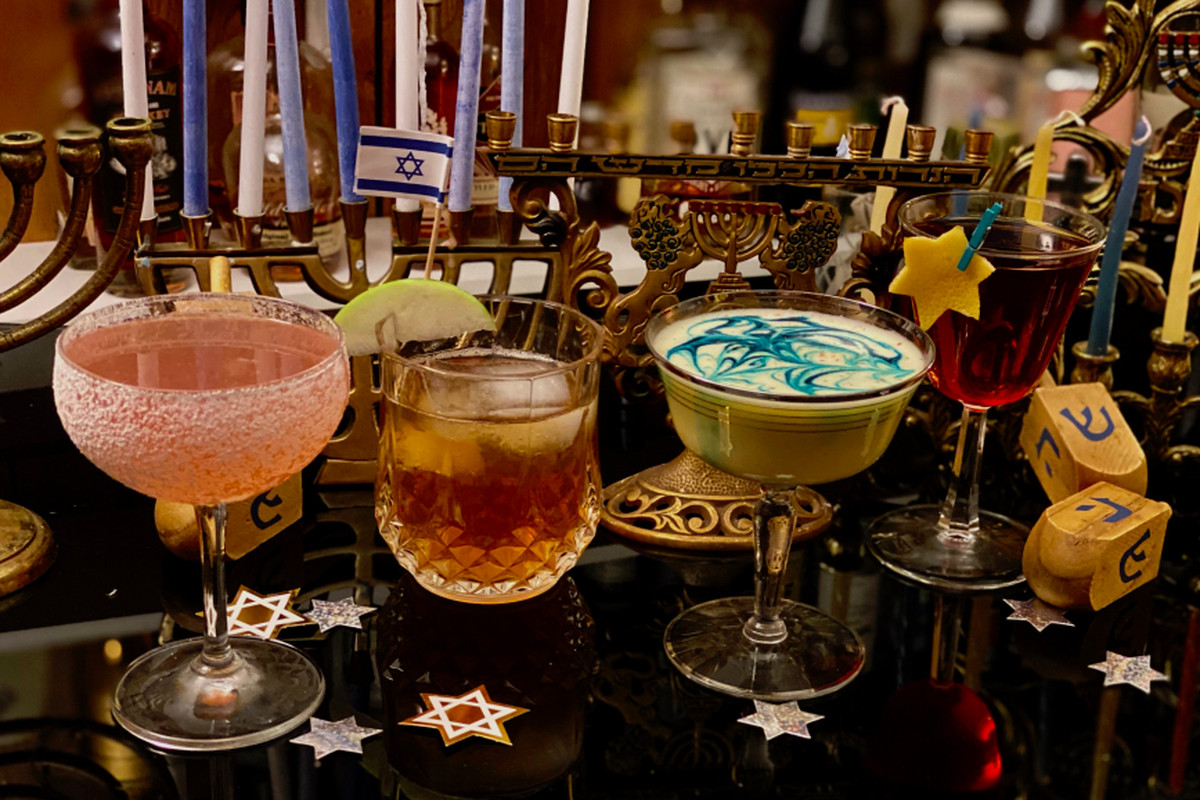 A lineup of Hanukkah-themed cocktails and Hanukkah paraphernalia, including a menorah and dreidels