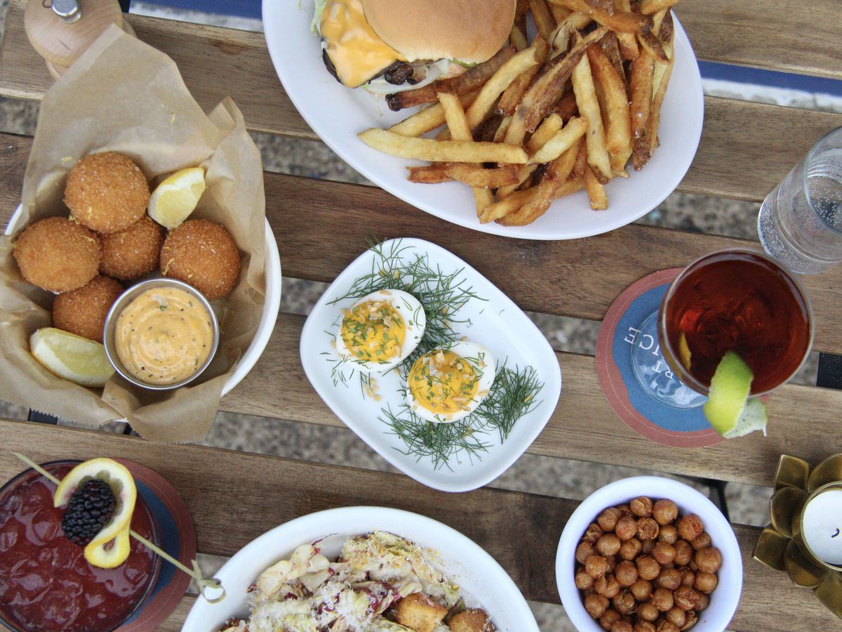 An overhead photograph of burgers, deviled eggs, and other dishes on a picnic table.