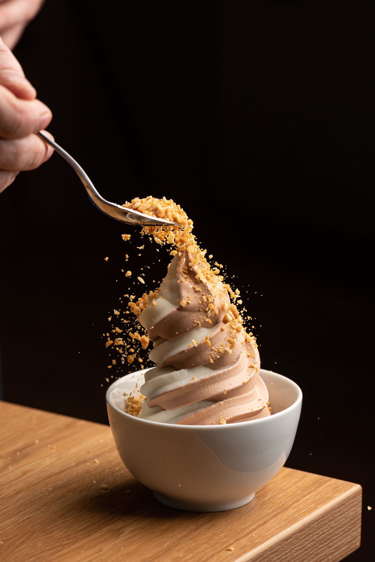 A swirl of mixed soft serve with nuts sprinkled on top in real time.