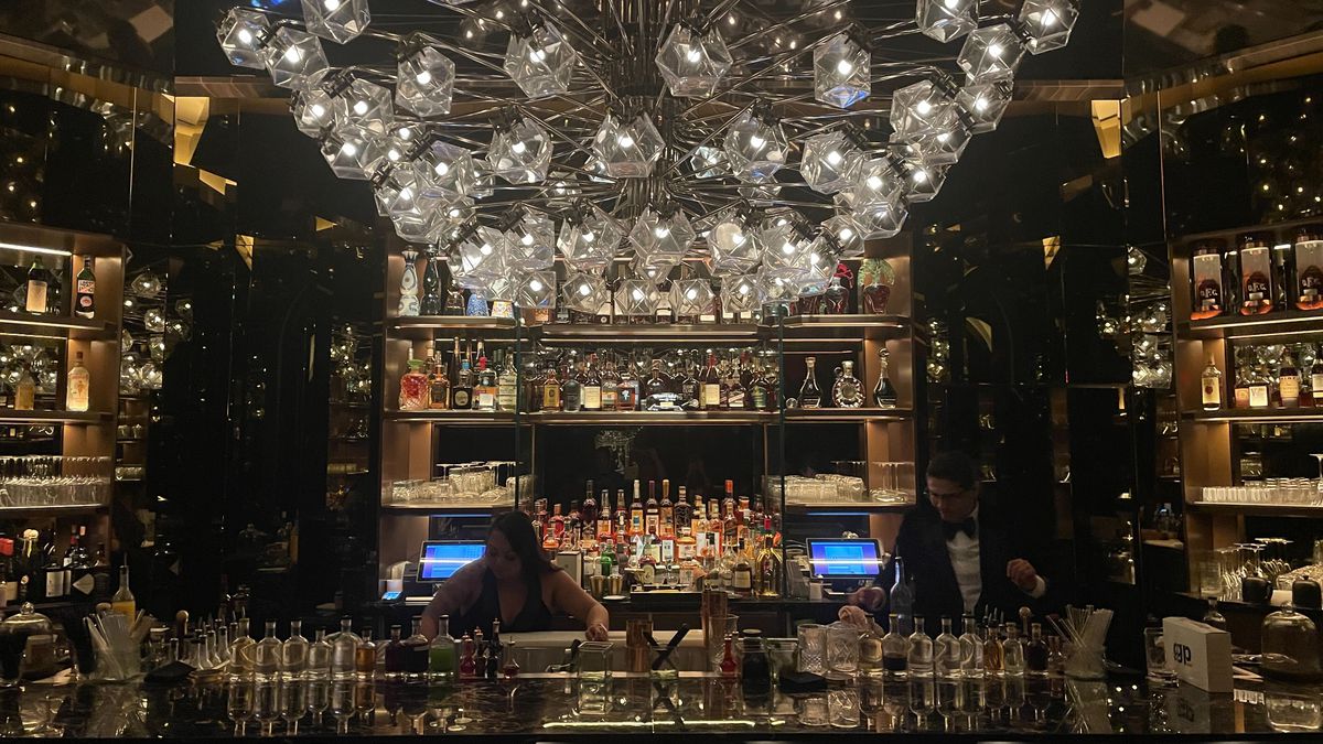 A glass chandelier over a bar.
